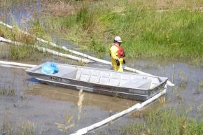 A park employee checks on containment booms used to stop the flow of oil from the Yellowstone River